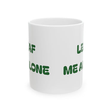 Glossy white ceramic mug with "Leaf Me Alone" funny plant pun and vibrant green leaf design